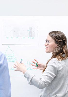 Professional explaining data and charts on a whiteboard during a collaborative discussion.
