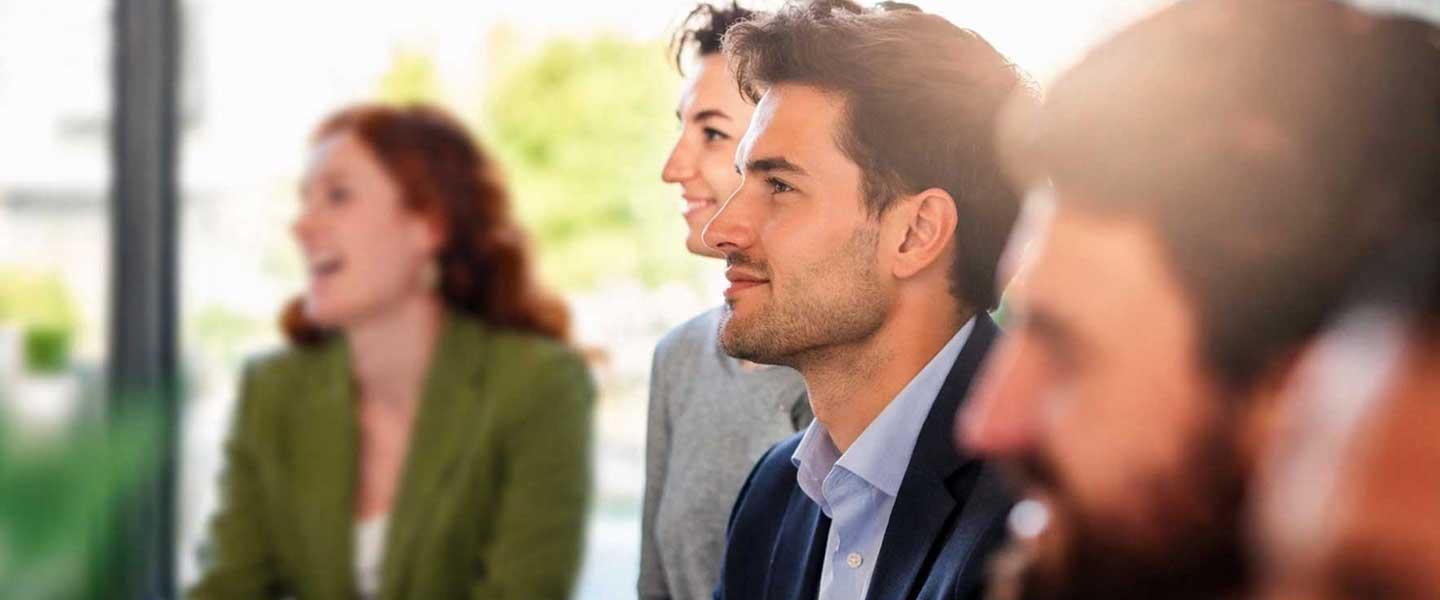 Professionals attentively listening during a business meeting or training session.