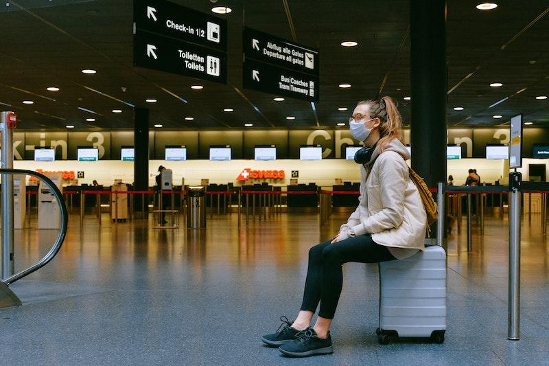 Mujer esperando en el aeropuerto con mascarilla