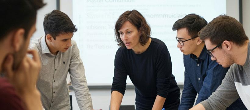 Professor guiding a group of students during a collaborative classroom activity.