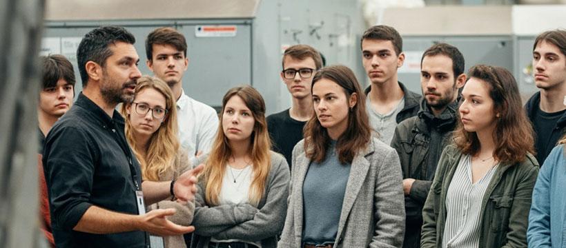 Group of students listening to a professional explaining equipment during an on-site visit.
