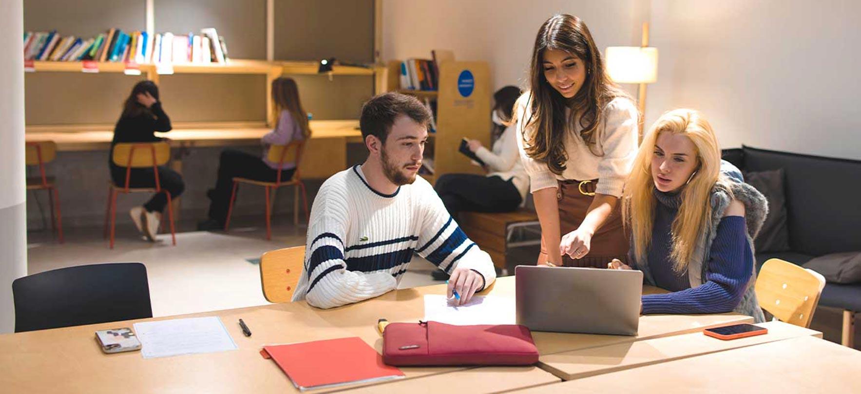 students collaborating on a group project with a laptop in a modern study space.